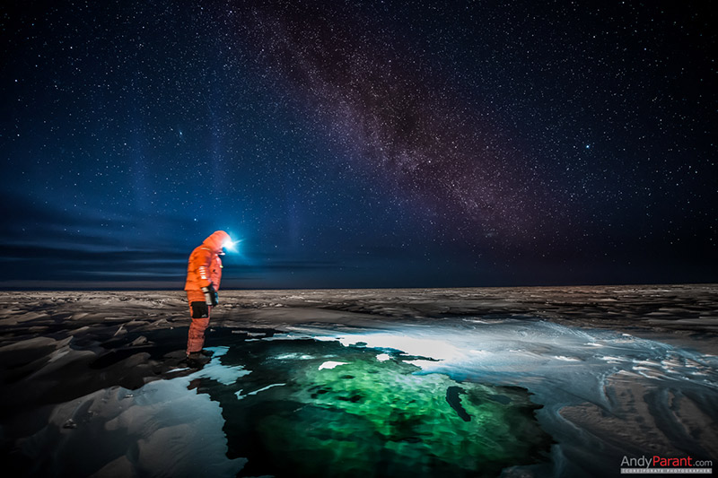 Explorateur à la frontale près d’un trou dans la glace, sous les étoiles